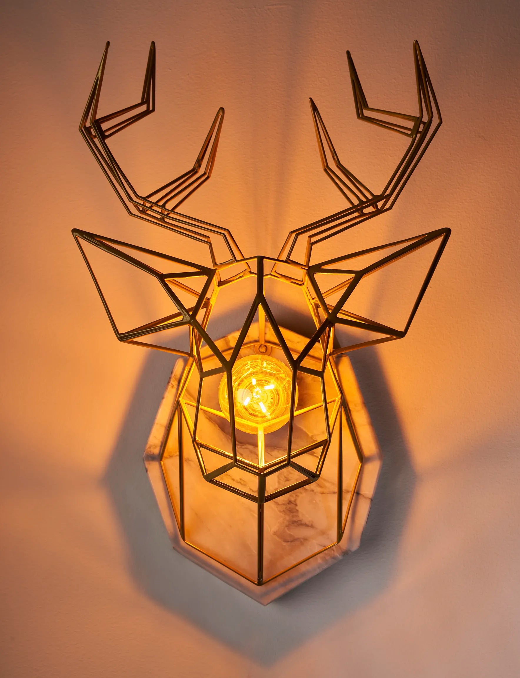 A geometric deer head wall art is attached to an eight-sided marble shape and hung on the wall