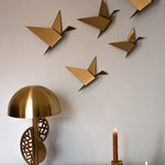 Five gold geometric pigeons in various sizes displayed as wall art