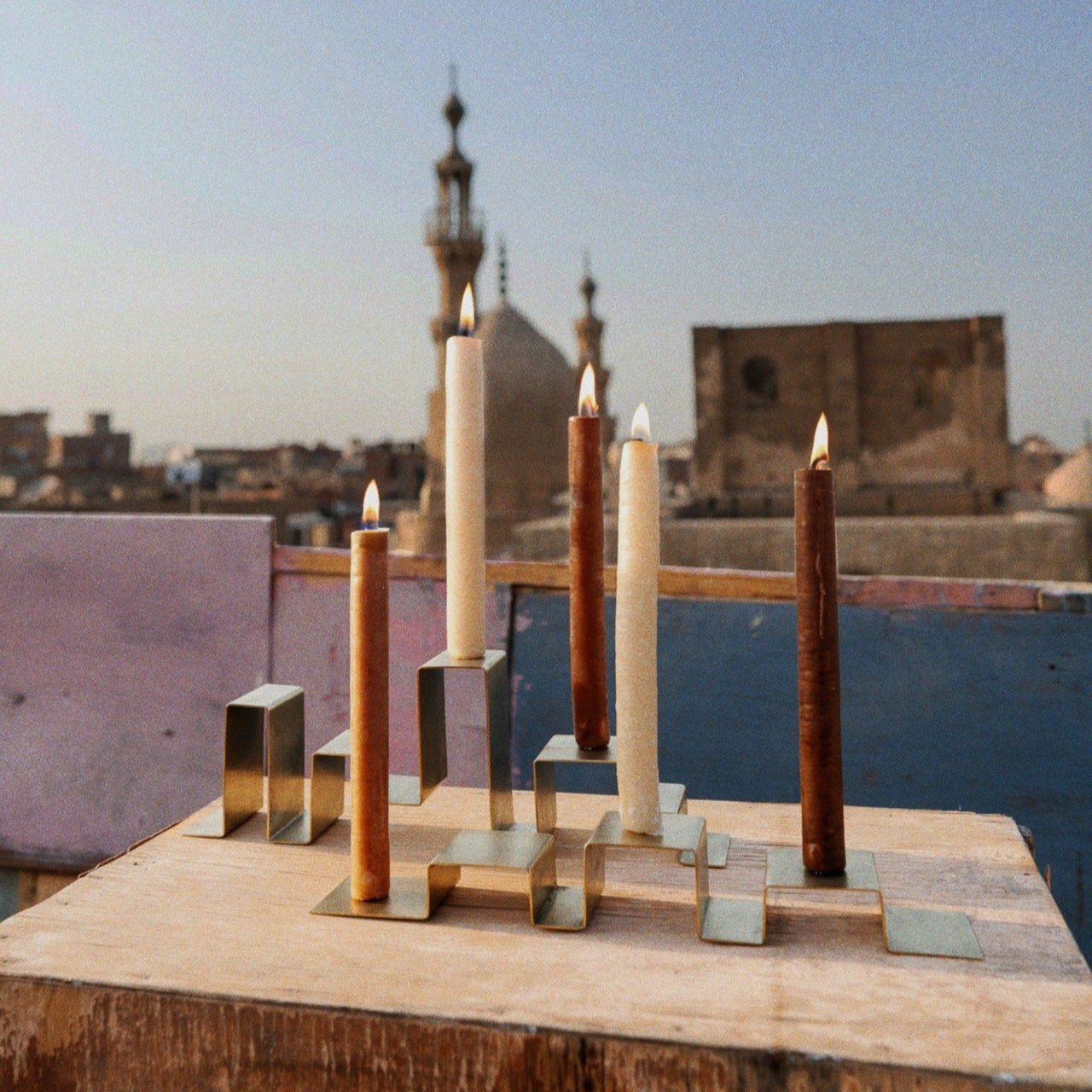 Two stainless steel candleholders holding a total of five candles, featured in a photoshoot on a rooftop in Egypt