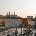 Two stainless steel candleholders holding a total of five candles, featured in a photoshoot on a rooftop in Egypt