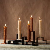 Two stainless steel candleholders holding a total of five candles, arranged on a table