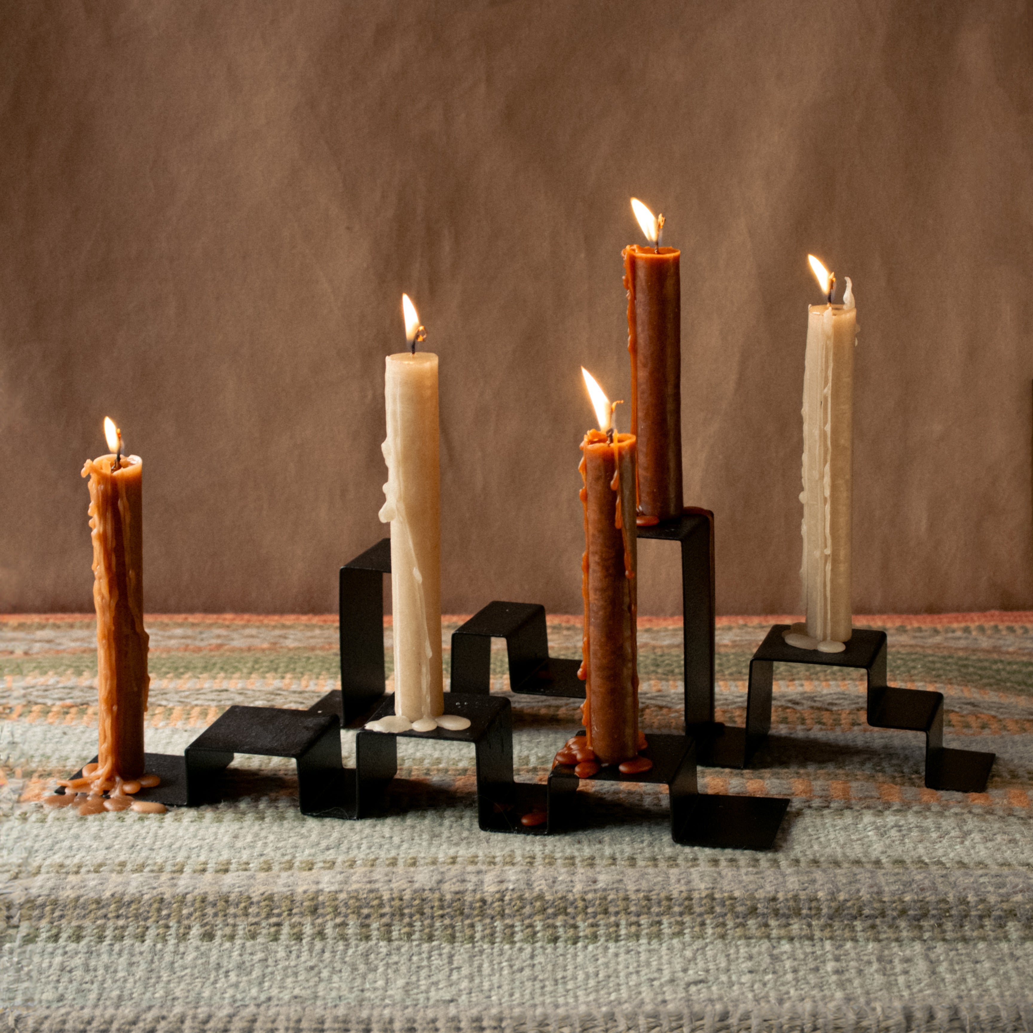 Two stainless steel candleholders holding a total of five candles, arranged on a table