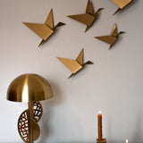 Five gold geometric pigeons in various sizes displayed as wall art