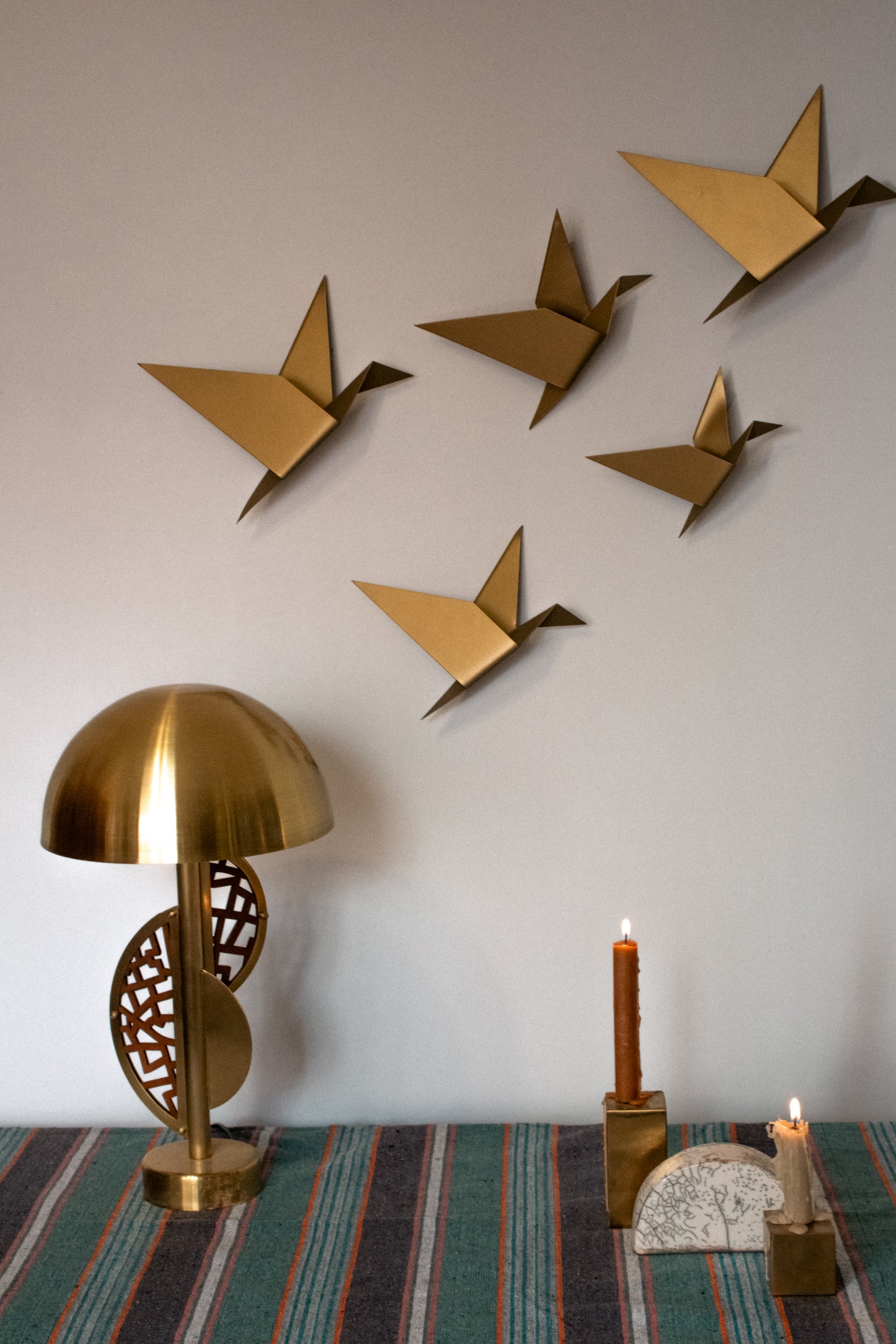 Five gold geometric pigeons in various sizes displayed as wall art