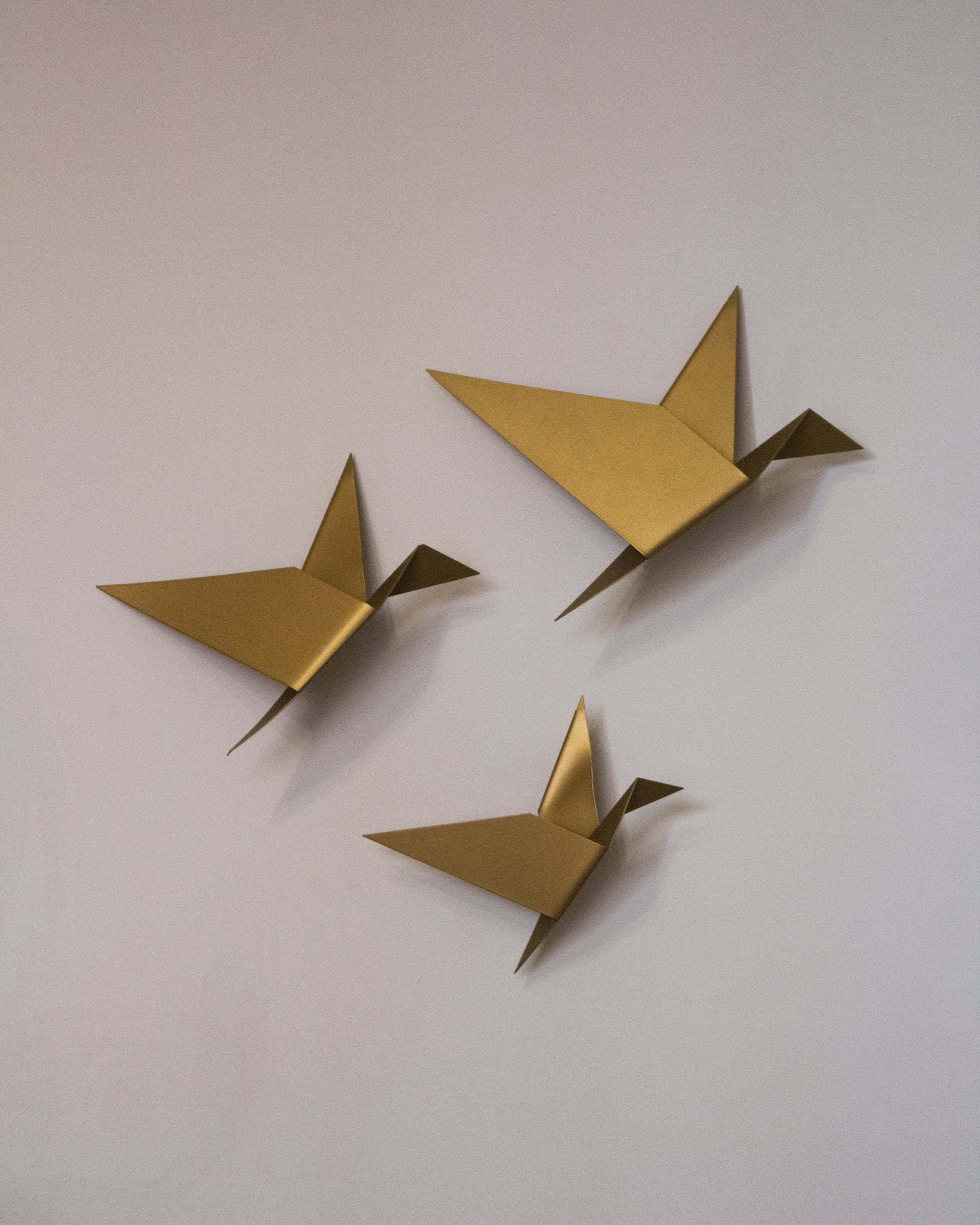 Three gold geometric pigeons in various sizes displayed as wall art