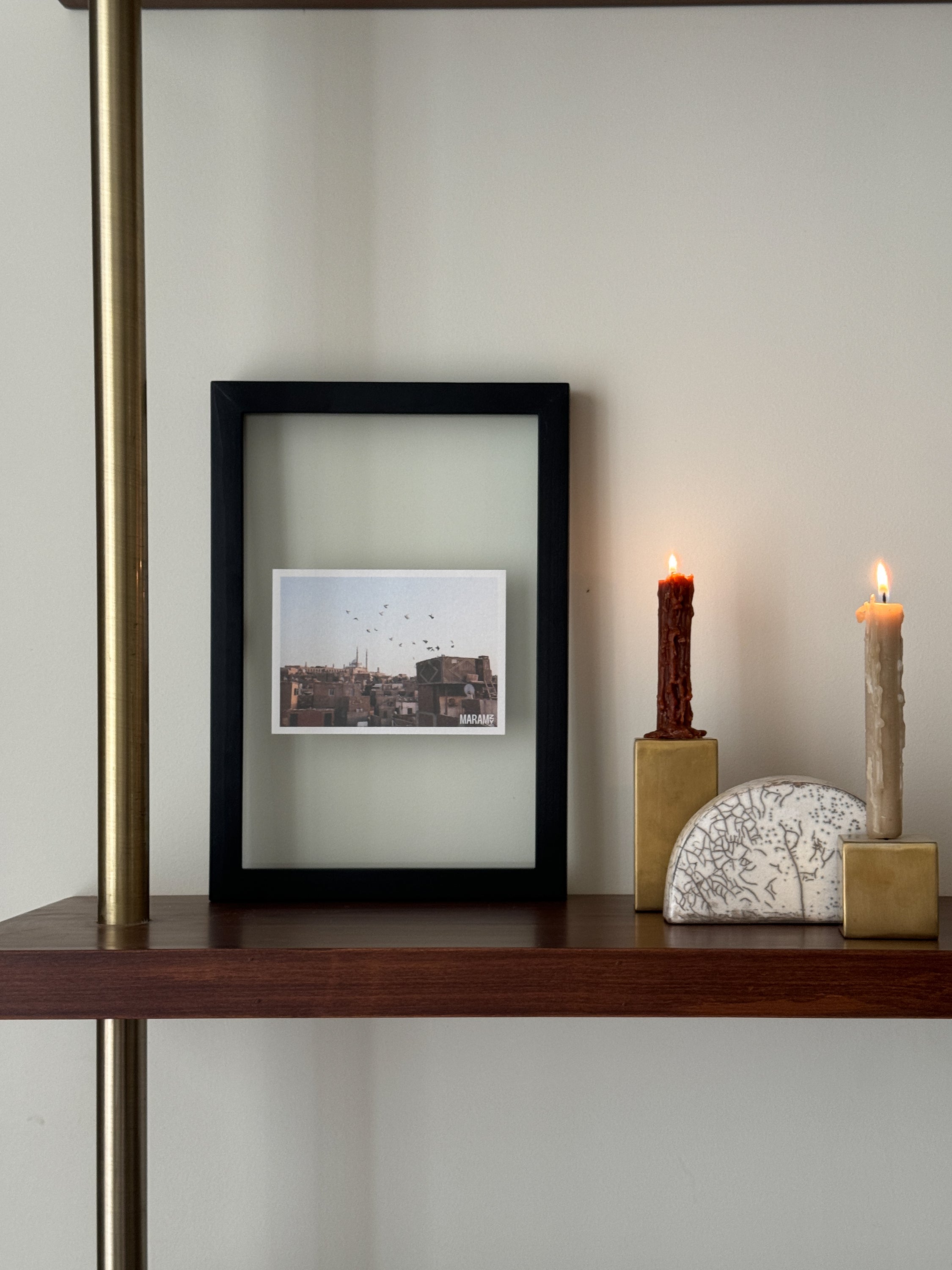 A small black wooden photo frame is placed on a shelf