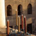 Two stainless steel candleholders holding a total of five candles set on a balcony