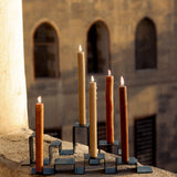 Two stainless steel candleholders holding a total of five candles set on a balcony